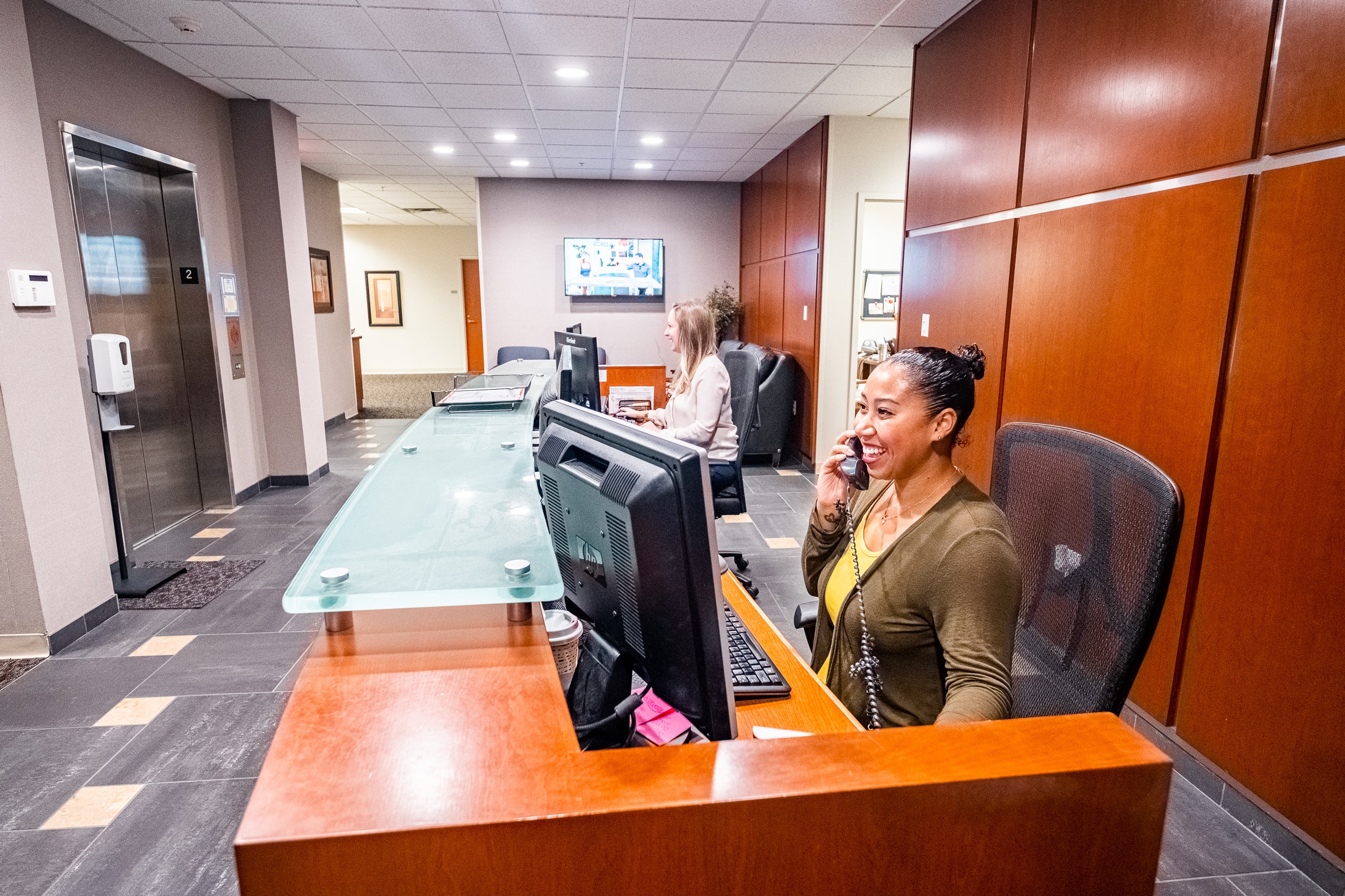 OSS Headquarters Virtual Receptionist. Smiling receptionist answering a phone in the lobby of an office building.